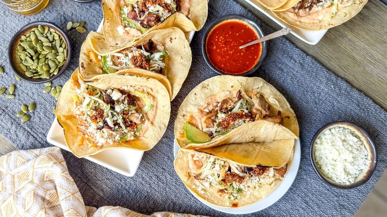 Grilled mushroom tacos with salsa macha crema on serving plater and plate with garnishes