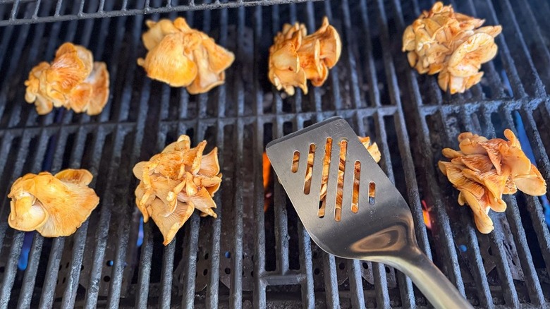 Grilling oyster mushroom clusters using large stainless steel spatula