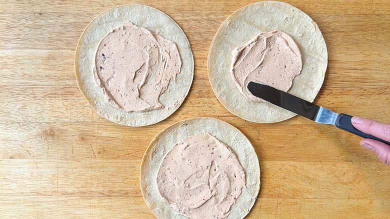 Spreading salsa macha crema on corn tortillas