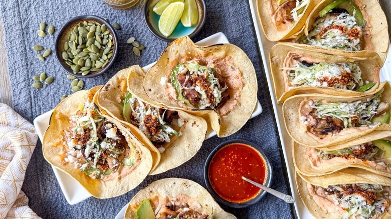 Grilled mushroom tacos with salsa macha crema on platter and plate with garnishes