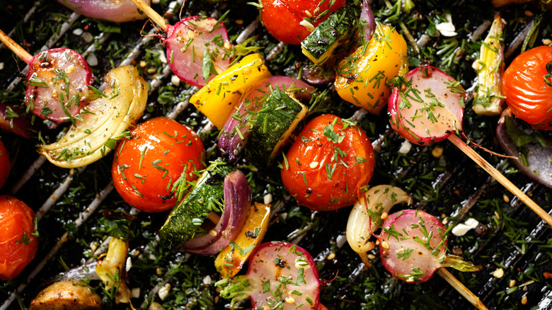 Grilled veggie skewers with cherry tomatoes, radishes, peppers and onions with fresh dill on a grill pan