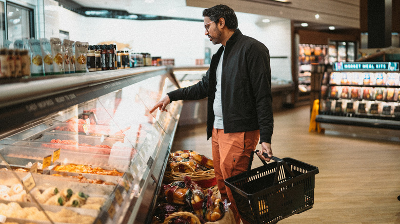 A man shopping at a grocery store deli
