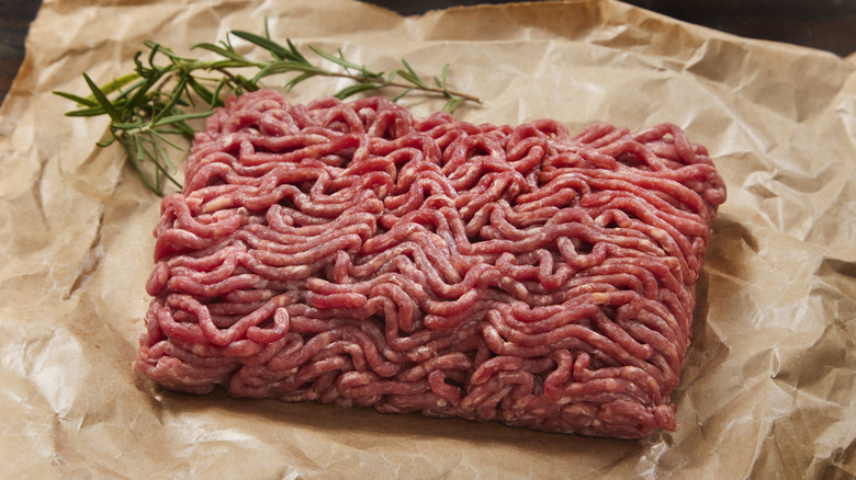 Raw ground beef with herbs on parchment
