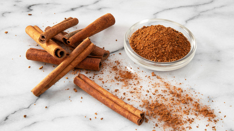 Marble table with cinnamon sticks and ground cinnamon.