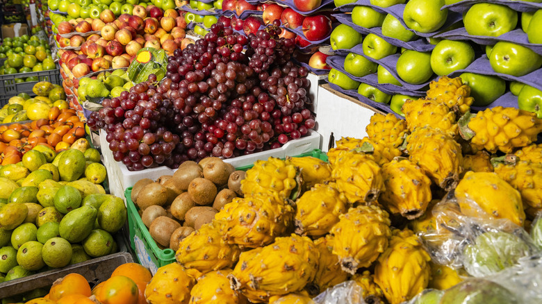 Apples, guava, kiwi, grapes, and other fruits on display at a market