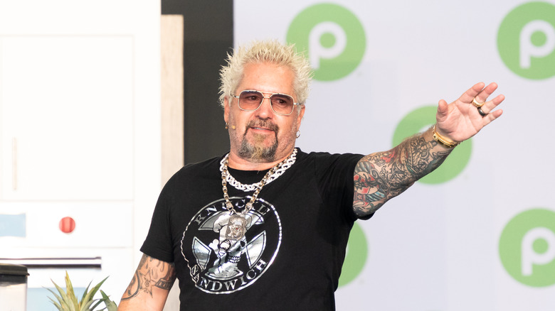 Guy Fieri holds his hand out at an event.
