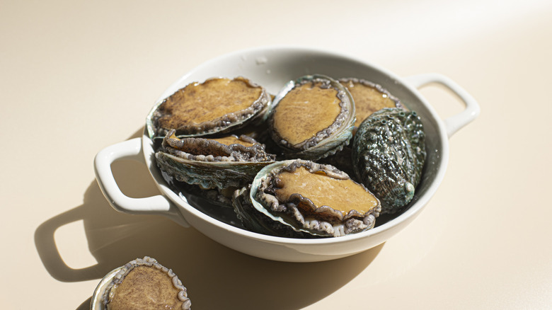 Raw abalone sit in a bowl.
