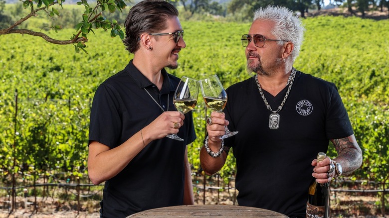 Guy Fieri and son hunter toasting wine glasses at their vineyard