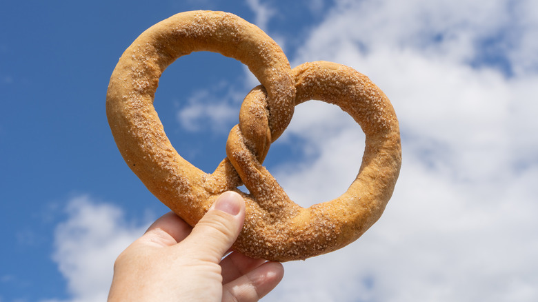 Hand holding a freshly-baked soft pretzel up to the sky