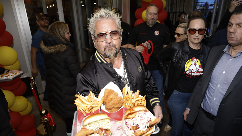 Celebrity chef Guy Fieri holds a tray of fried foods.