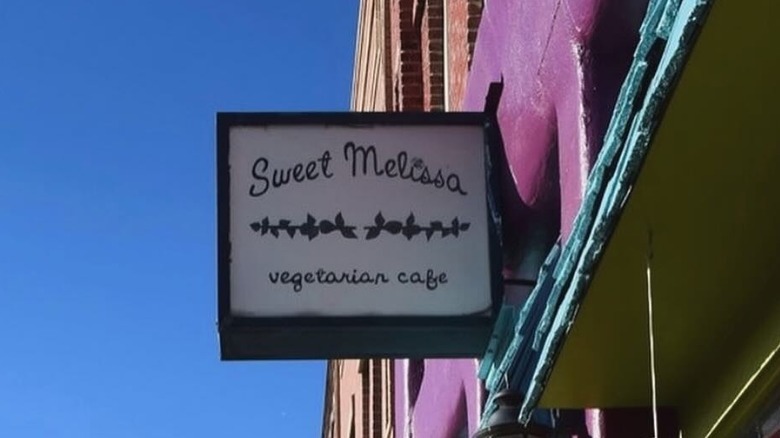The sign outside Sweet Melissa Vegetarian Cafe with blue sky in the background