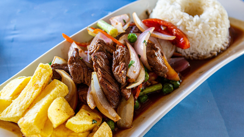 A plate of lomo saltado with rice, beef, and fries