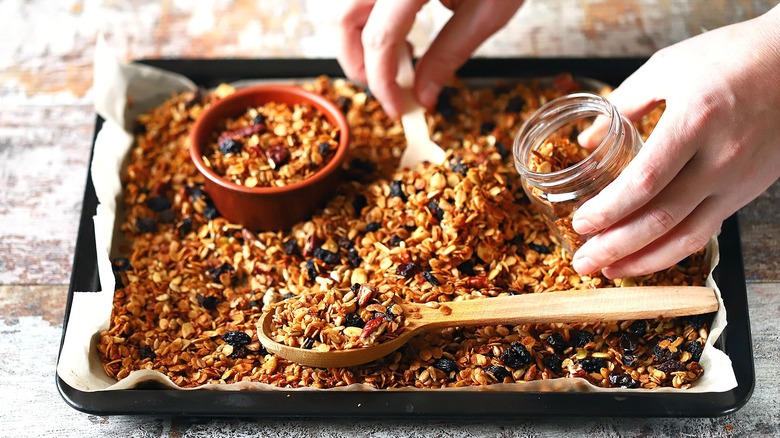Freshly-baked granola on baking pan with wooden spoon