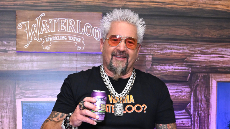 Guy Fieri smiling and holding a can of Waterloo sparkling water