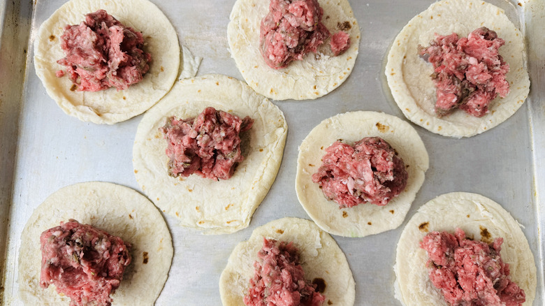 Raw ground lamb placed over tortillas