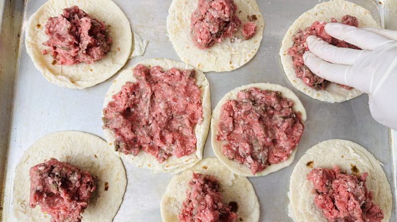 Pressing ground lamb onto tortillas