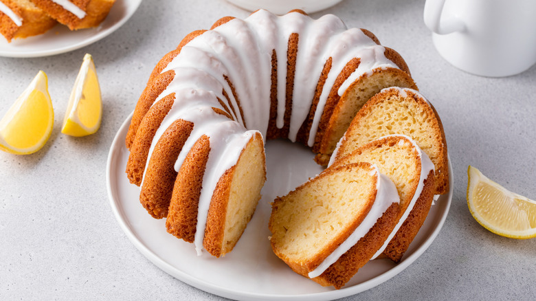 Sliced and frosted Bundt cake surrounded by lemon slices on a white countertop