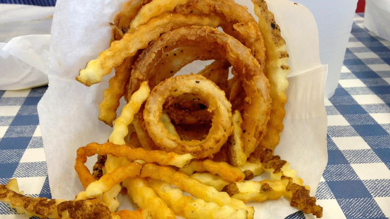 A mix of onion rings and french fries in one serving