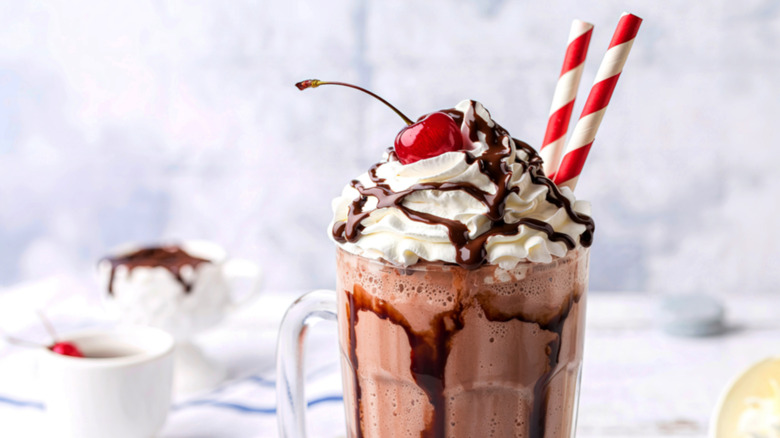 A fancy chocolate milkshake with striped straws