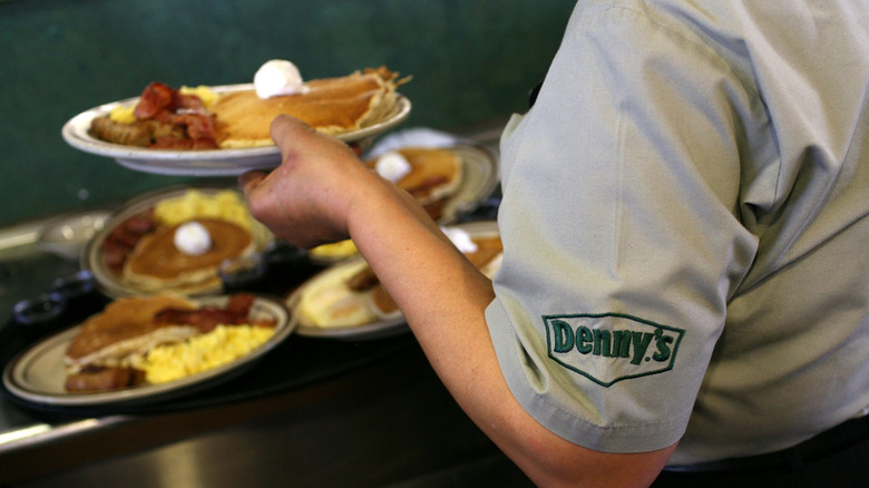 A server at Denny's pulls food items out of the kitchen window