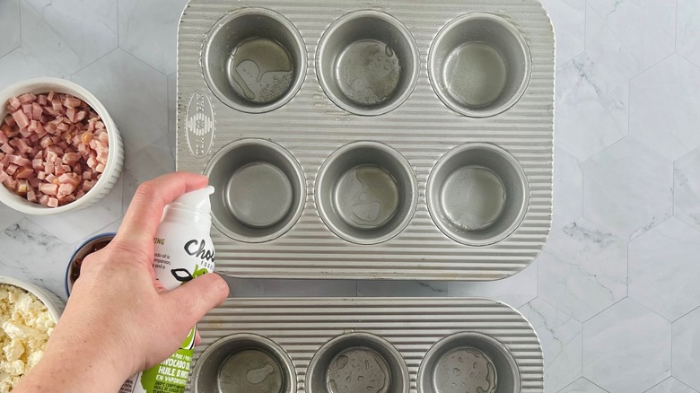 hand spraying muffin pan