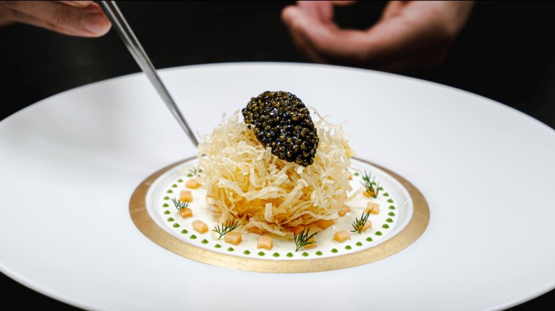 Egg, smoked salmon, and caviar on a white plate with gold decorations