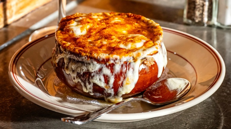 French onion soup in a crock on a stone plate with a spoon