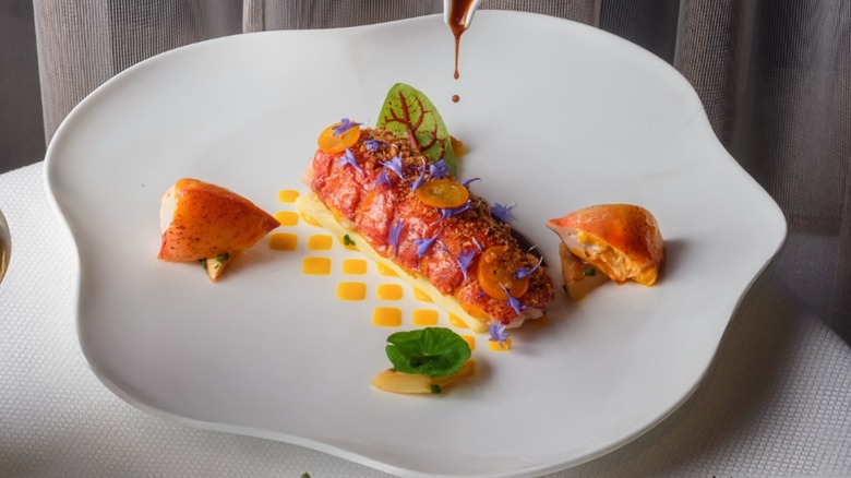 Lobster tail dish with a rich sauce on a white plate