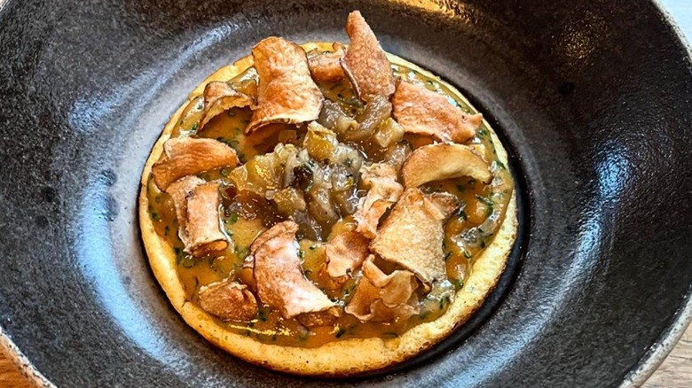 Sunchoke Spoonbread - Yuzu & Pear Chutney, Sage, salt and vinegar "chips" on a rustic black plate