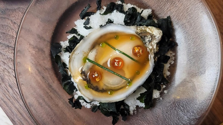 Raw oyster on the half shell on a decorative glass plate