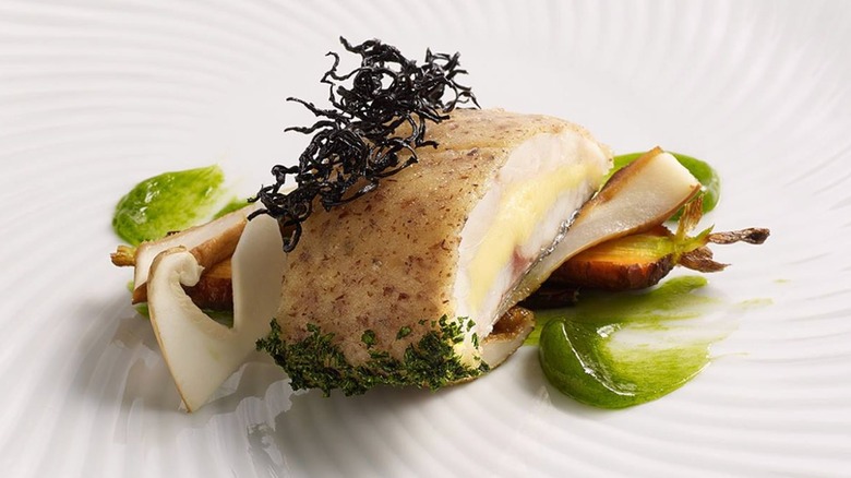 Mediterranean Lubina Brioche "Panade," Black Trumpet Mushrooms, Sweet Carrots and "Barigoule" Purée on a white plate