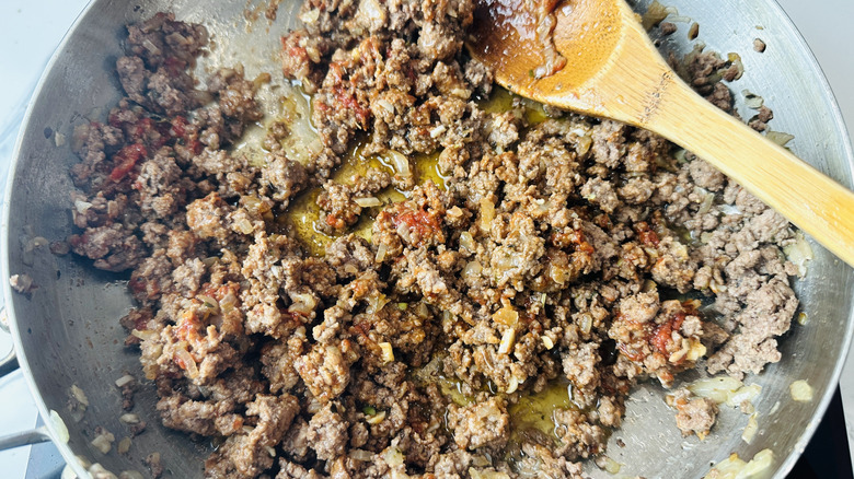Tomato paste coating beef in saucepan