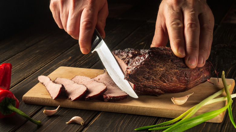 Well-done steak being sliced on a cutting board