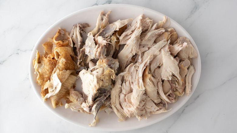 shredded chicken and chicken skin on a white plate