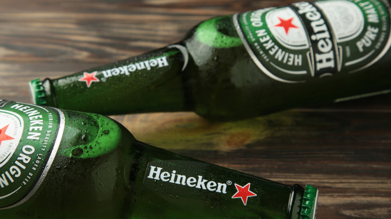 Two bottles of Heineken on a wooden table.
