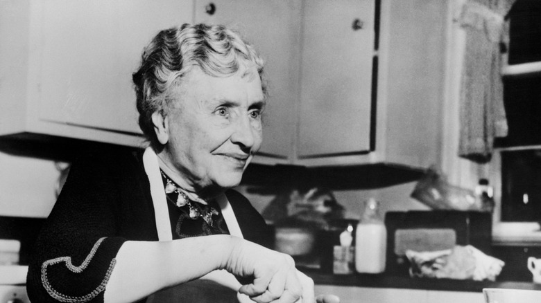 Black and white photo of Helen Keller in a kitchen.