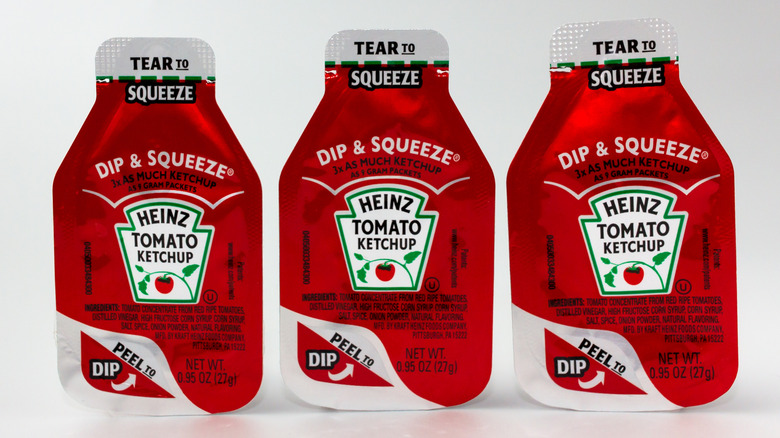 Three Heinz dip and squeeze ketchup packets on white background