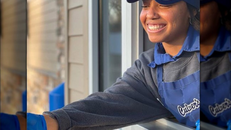 Drive through worker handing order out the window to a car