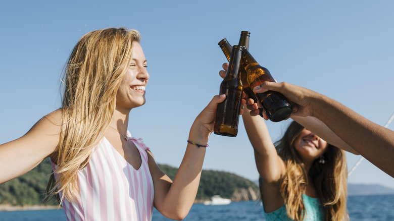 Three people making a beer bottle toast on beach