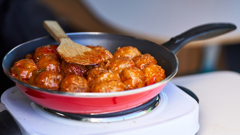 meatballs simmering in sauce on a hot plate