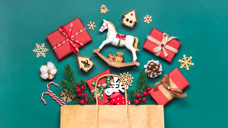 A brown paper bag with holiday-themed items spilling out to reveal its contents, set against a dark teal background