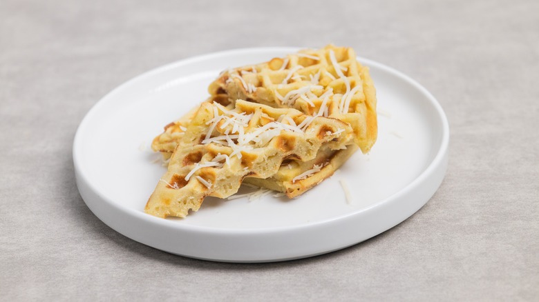 Waffles topped with grated cheese on a white plate