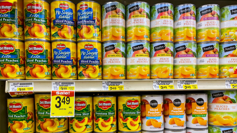 Grocery store shelves of canned peaches and one section of cans is marked with a sale tag