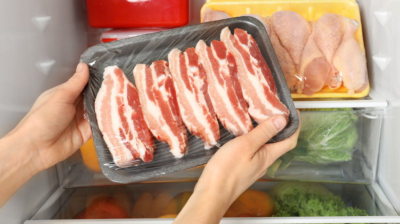 hands holding refrigerated bacon packe