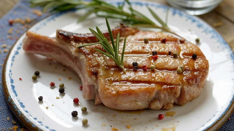 Cooked bone-in pork chop with a spring of rosemary