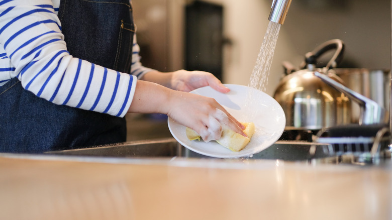 a woman washing dishes by hand