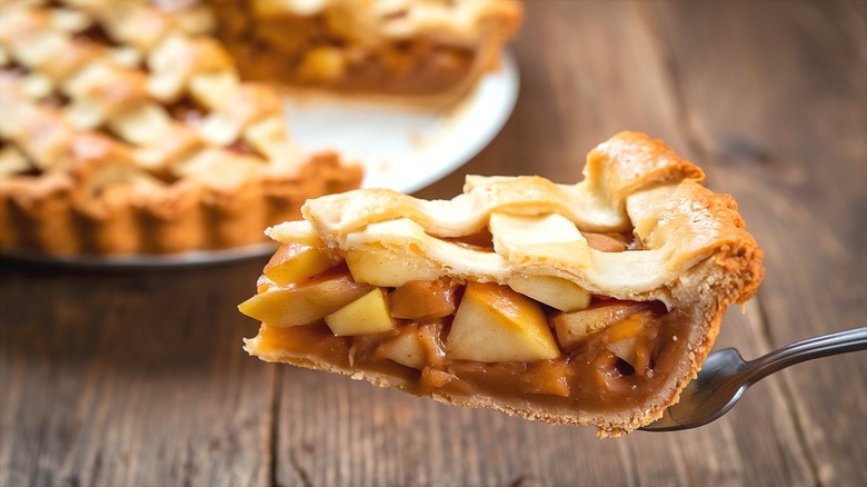 A piece of apple pie with lattice-style crust on a serving fork.
