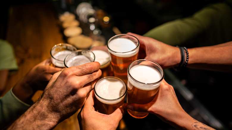 A group of friends clinking beer glasses at a pub