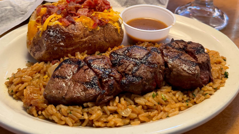 Texas Roadhouse steak medallions over rice with a loaded baked potato