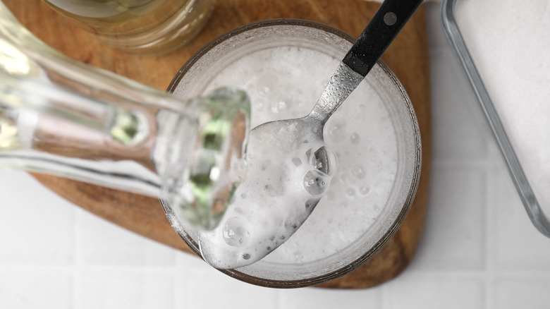 pouring vinegar onto a spoon with baking soda